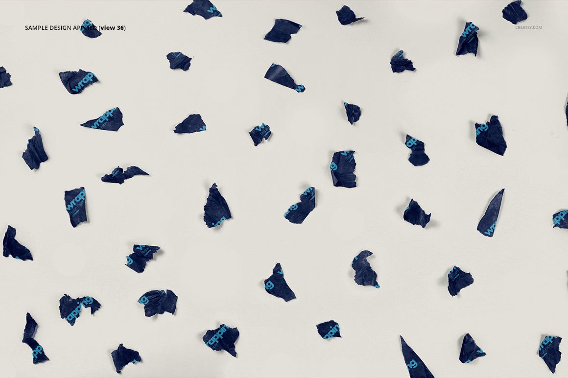 Mockup showing irregular navy blue tissue paper scraps with blue text spread across a light background, overhead perspective.