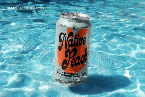 Mockup of a tilted drink can in bright blue pool water, surrounded by ripples and droplets, close-up perspective.
