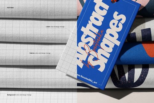PSD mockup of stacked jersey fabrics with grid and abstract patterns, accompanied by a blue rectangular paper tag.