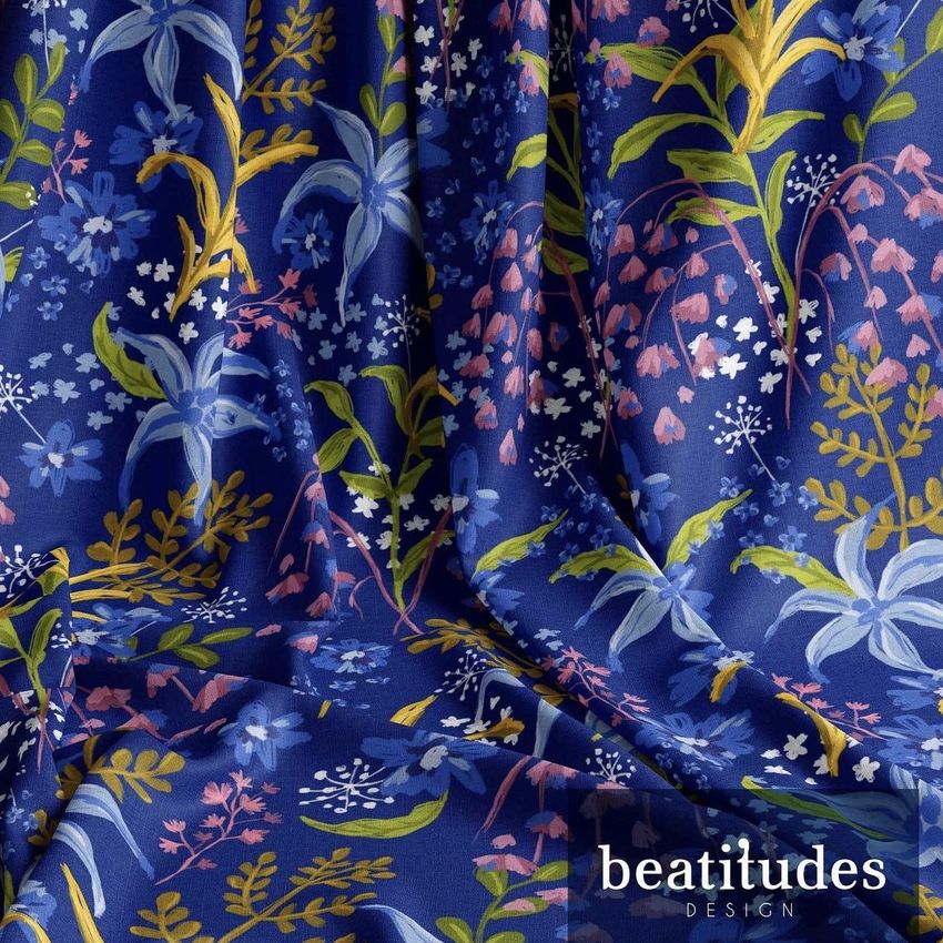 Draped fabric mockup featuring a blue textile with a colorful floral pattern in yellow, green, and pink tones, viewed close up.