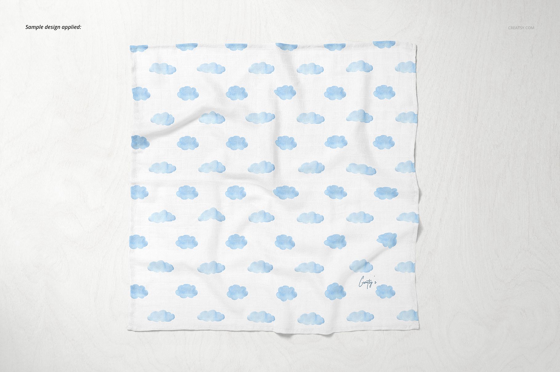 Square baby muslin nappy mockup with a repeating blue cloud pattern, shown from a top view on a light surface.