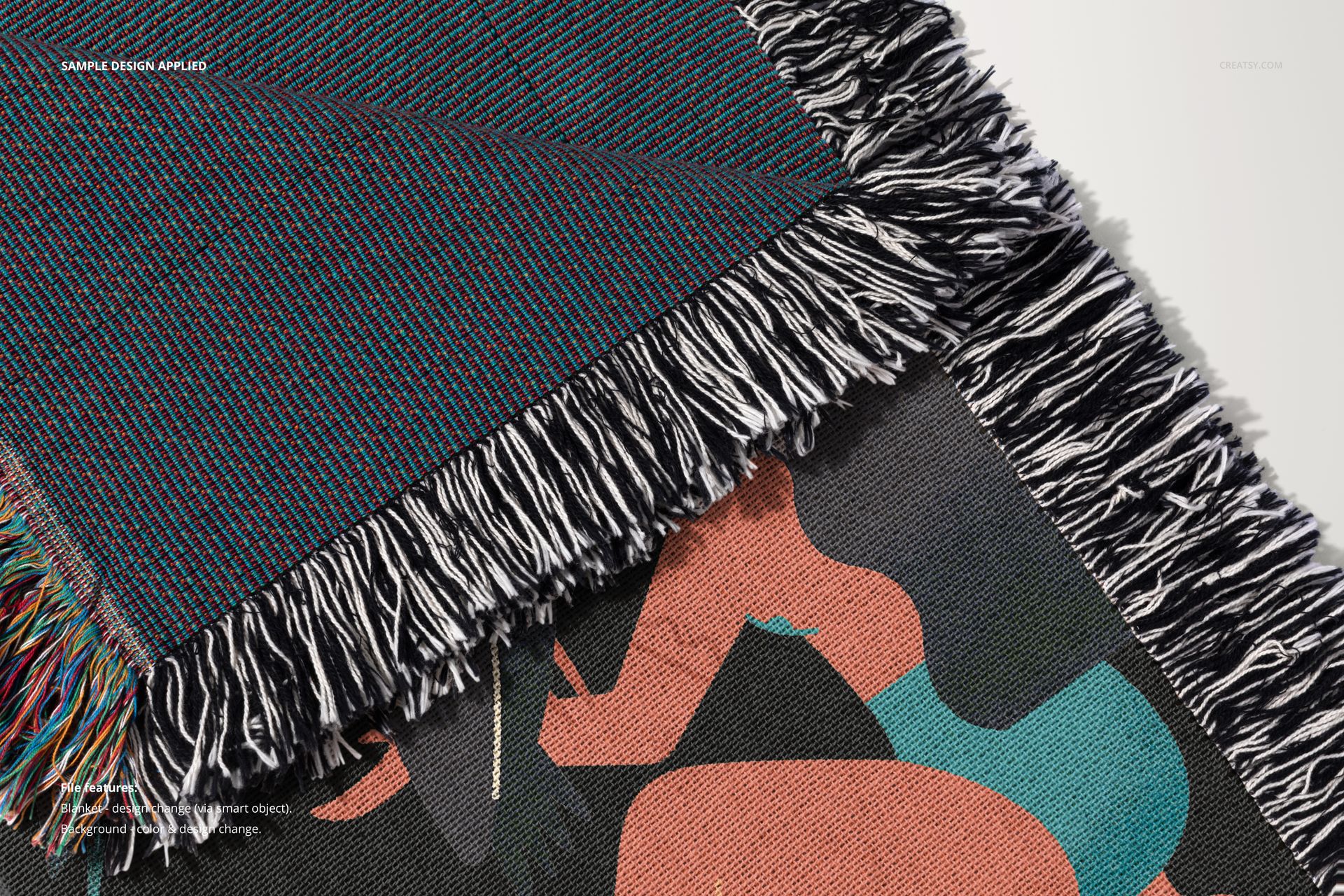 Close-up of a woven throw blanket mockup with black and white fringe and abstract design in teal and peach tones.