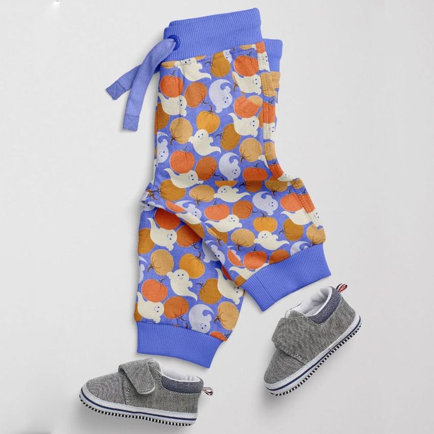 Baby sweatpants mockup featuring a playful Halloween-themed pattern with orange and purple pumpkins, shown with gray baby shoes on a light surface.