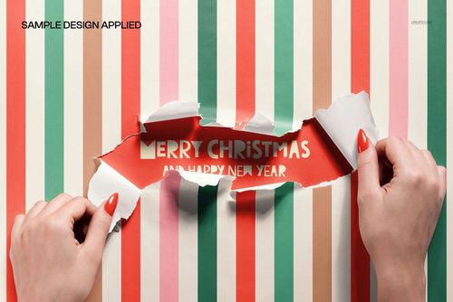PSD mockup showing hands opening colorful striped wrapping paper with a Merry Christmas message revealed inside.