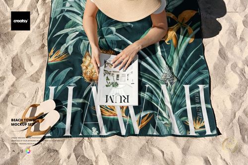 Beach towel mockup featuring a tropical design with pineapples and leaves, shown on sand with a person reading.