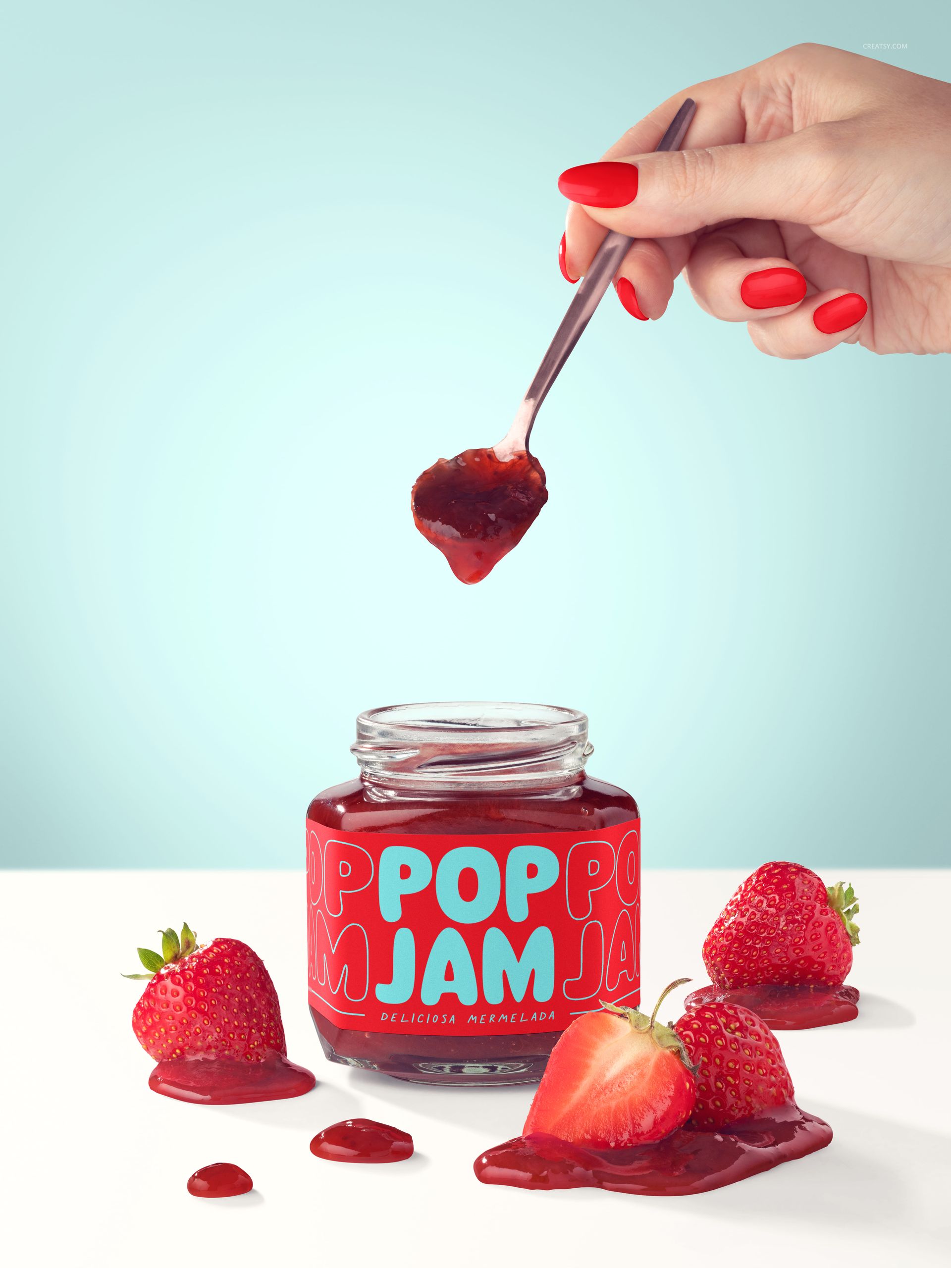 Strawberry jam jar mockup with bold red label, fresh strawberries, and a hand lifting jam with a spoon.