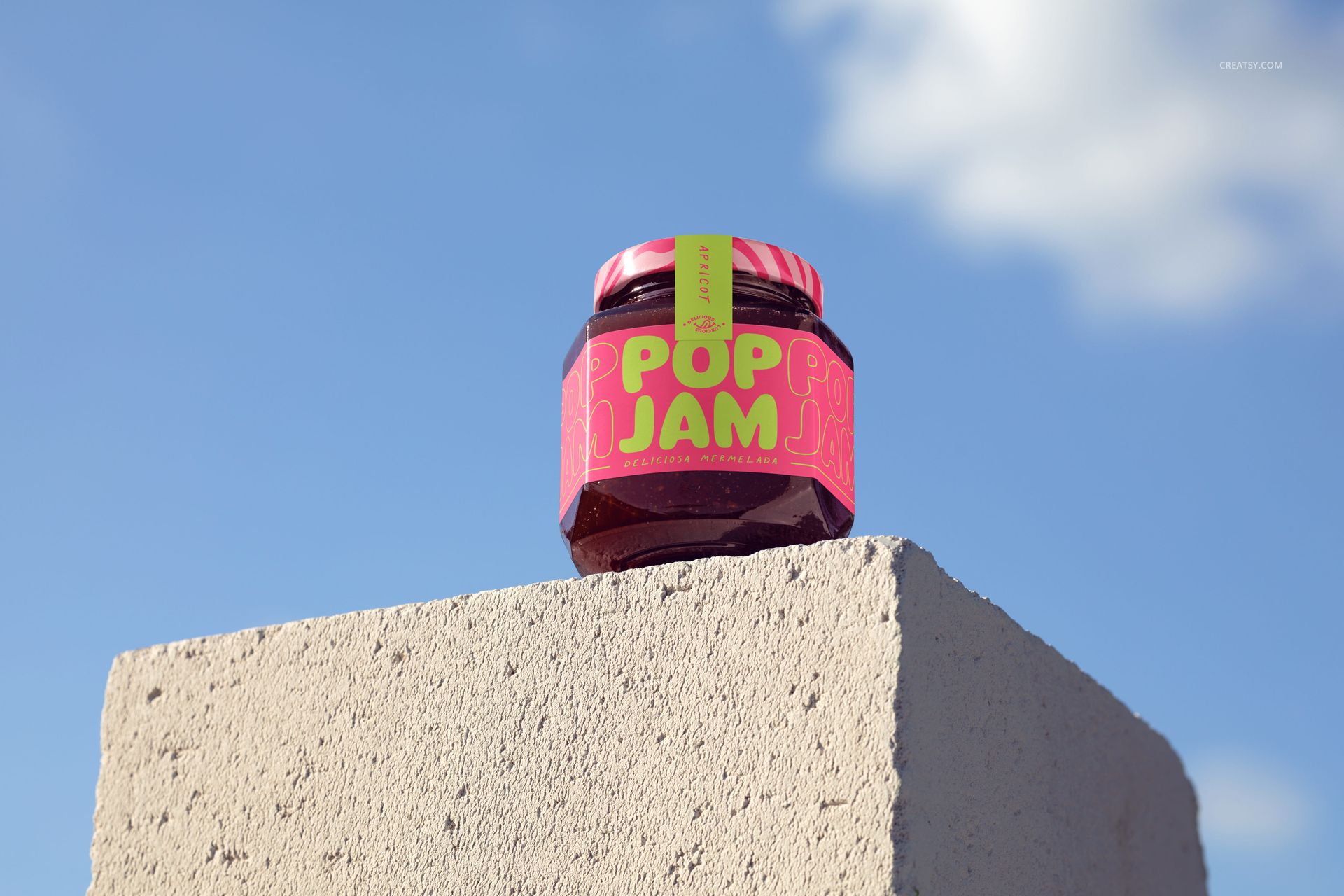 Front view of a jam jar mockup featuring a colorful label, set atop a rough concrete block with a clear sky background.