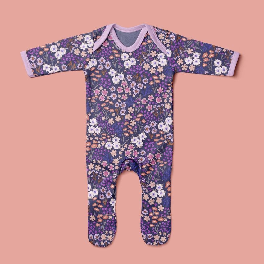 Baby chest rompersuit mockup featuring a ditsy floral pattern in purple, pink, and white on a solid peach background.