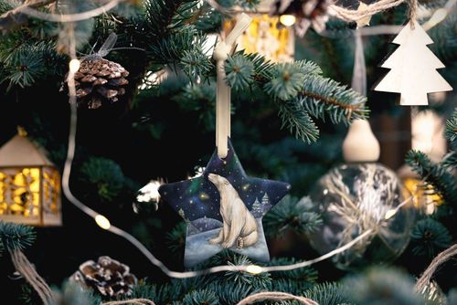 Star-shaped Christmas ornament mockup featuring a polar bear design, hanging on a decorated tree with lights.