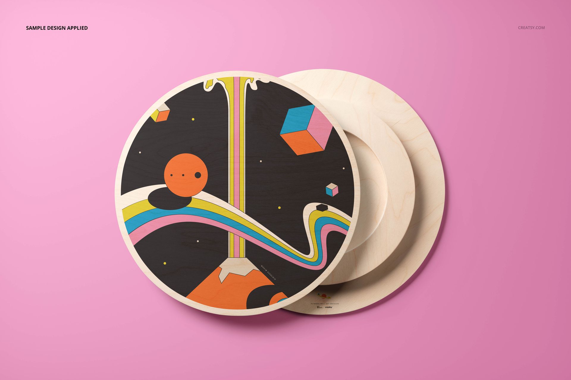 Round plywood wall art mockup with colorful abstract design on a pink background, shown from a front angle.