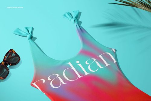 Flat lay of a vibrant one-piece swimsuit mockup featuring a multicolor design and large white lettering on the front.