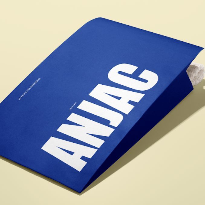 Kraft mailer mockup featuring a bold blue envelope with large white text, shown on a light beige background with tissue paper inside.