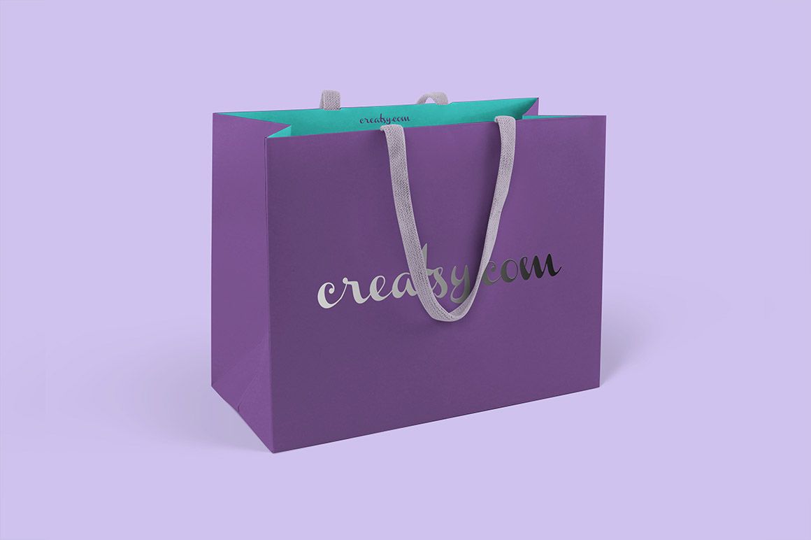 Purple paper bag mockup with silver lettering and gray handles, displayed on a pastel lavender surface.