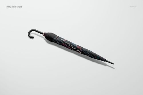 Folded umbrella mockup with black handle and dark patterned cover, shown from a side view on a plain surface.