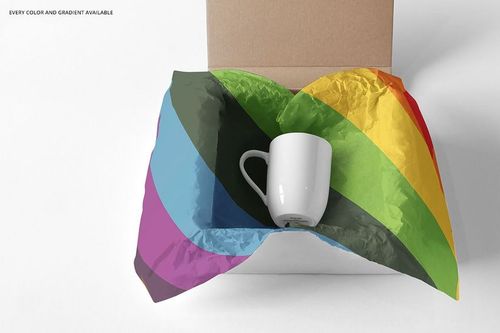 Mailing box mockup featuring a white mug and vibrant rainbow-striped wrapping paper on a neutral white surface.