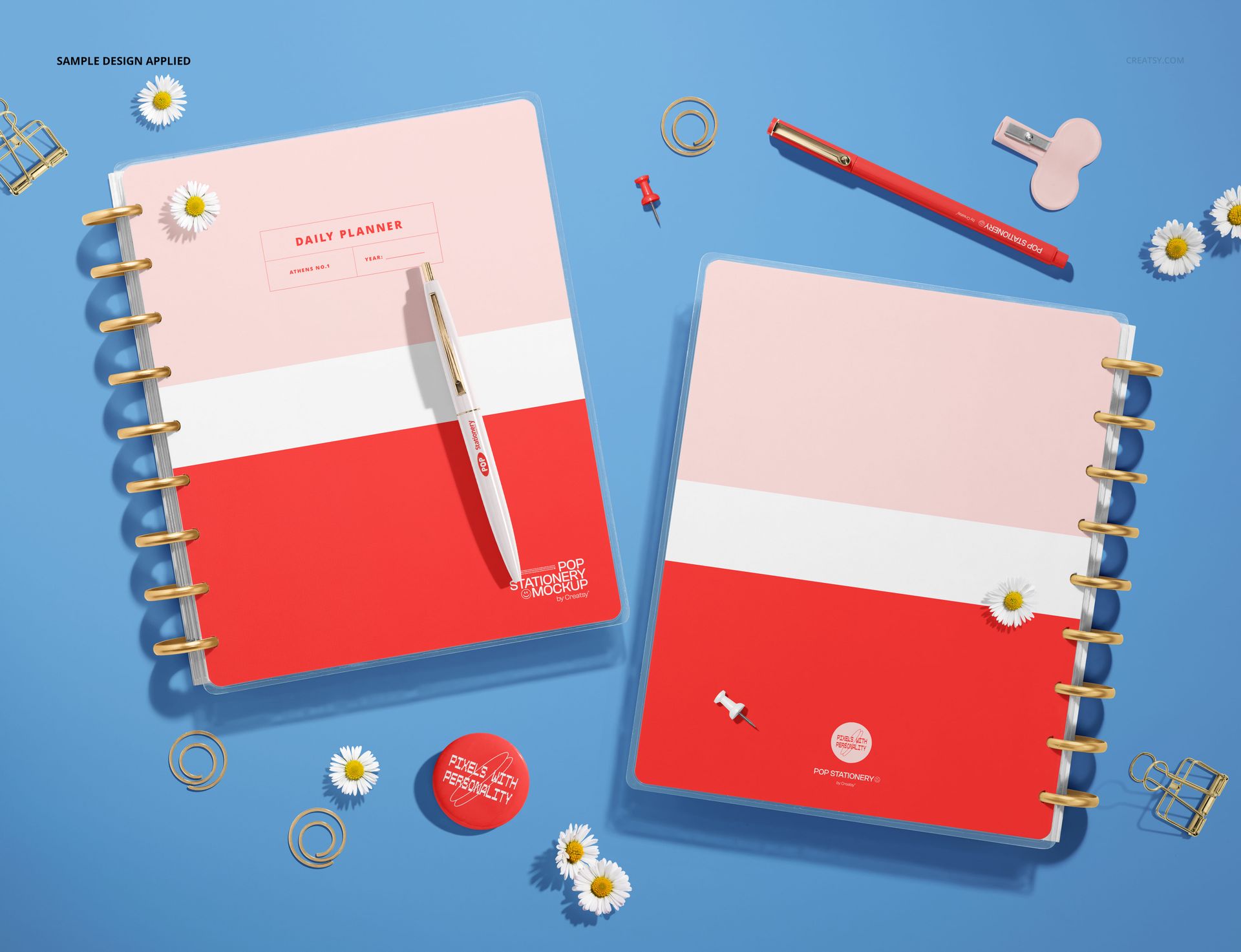 Spiral planner mockup showing back and front covers with pink and red color blocks, arranged on a blue surface.