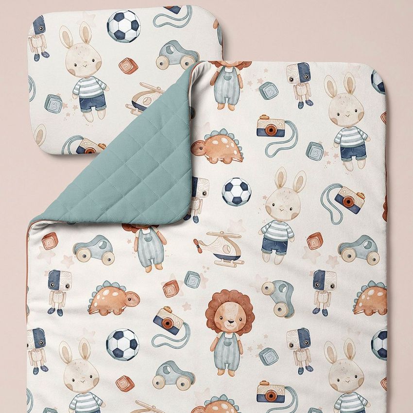 Double-sided baby bedding mockup featuring a pillow and quilt with playful animal and toy illustrations on a soft background.