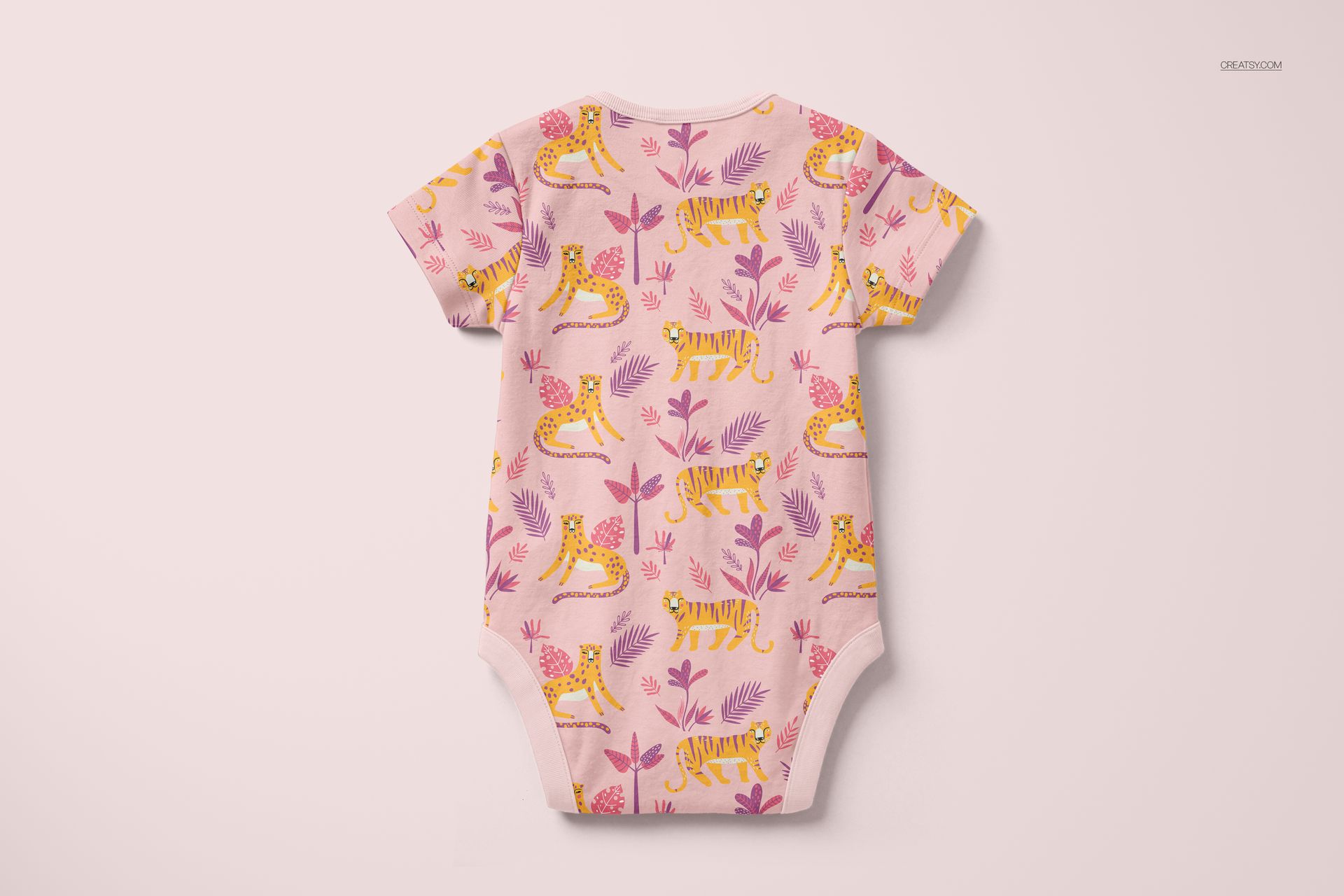 Back view of a short-sleeved baby bodysuit mockup featuring yellow tigers and pink foliage on a pale surface.
