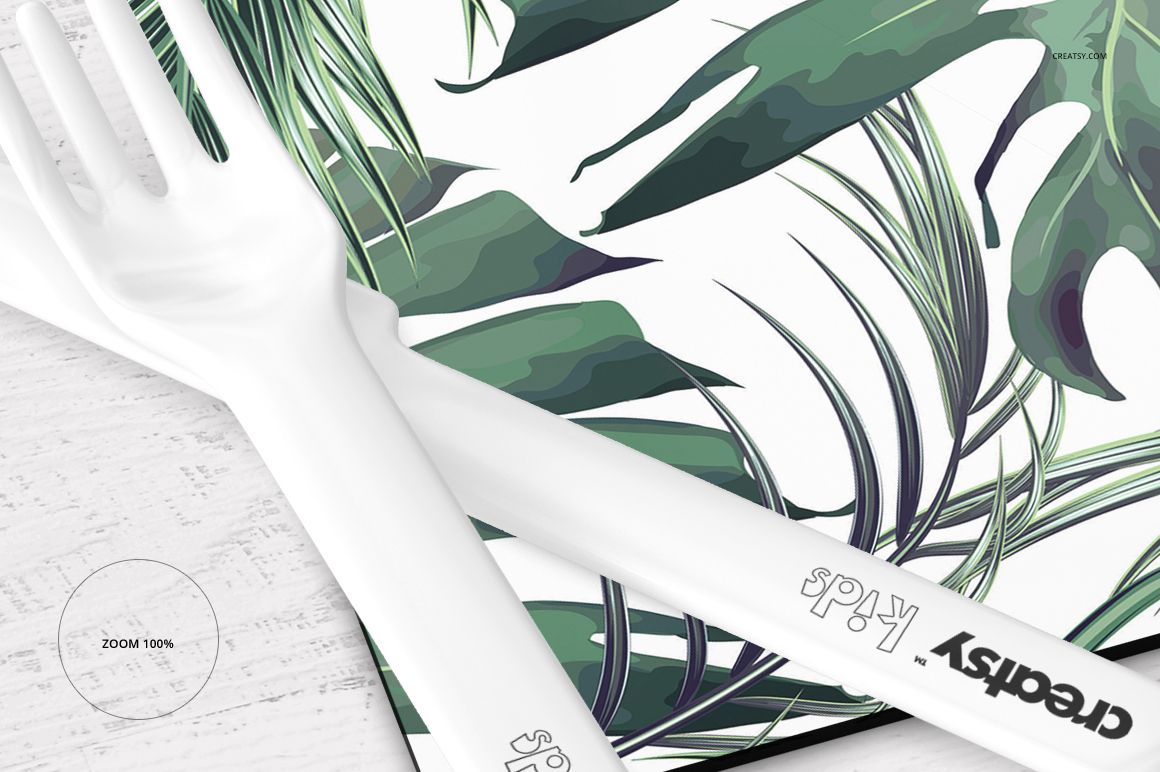 Placemat and coaster set mockup featuring a tropical leaf pattern, shown in a close-up view with white plastic cutlery.