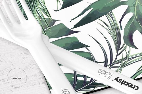 Placemat and coaster set mockup featuring a tropical leaf pattern, shown in a close-up view with white plastic cutlery.