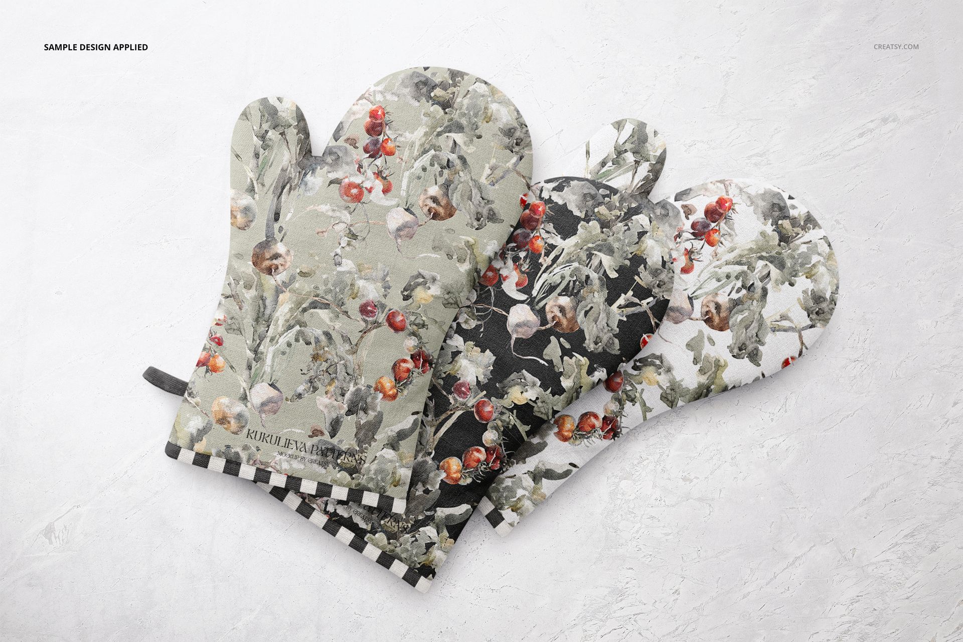 Oven mitt PSD mockup showing three mitts with nature-inspired prints on a pale stone background, viewed from above.