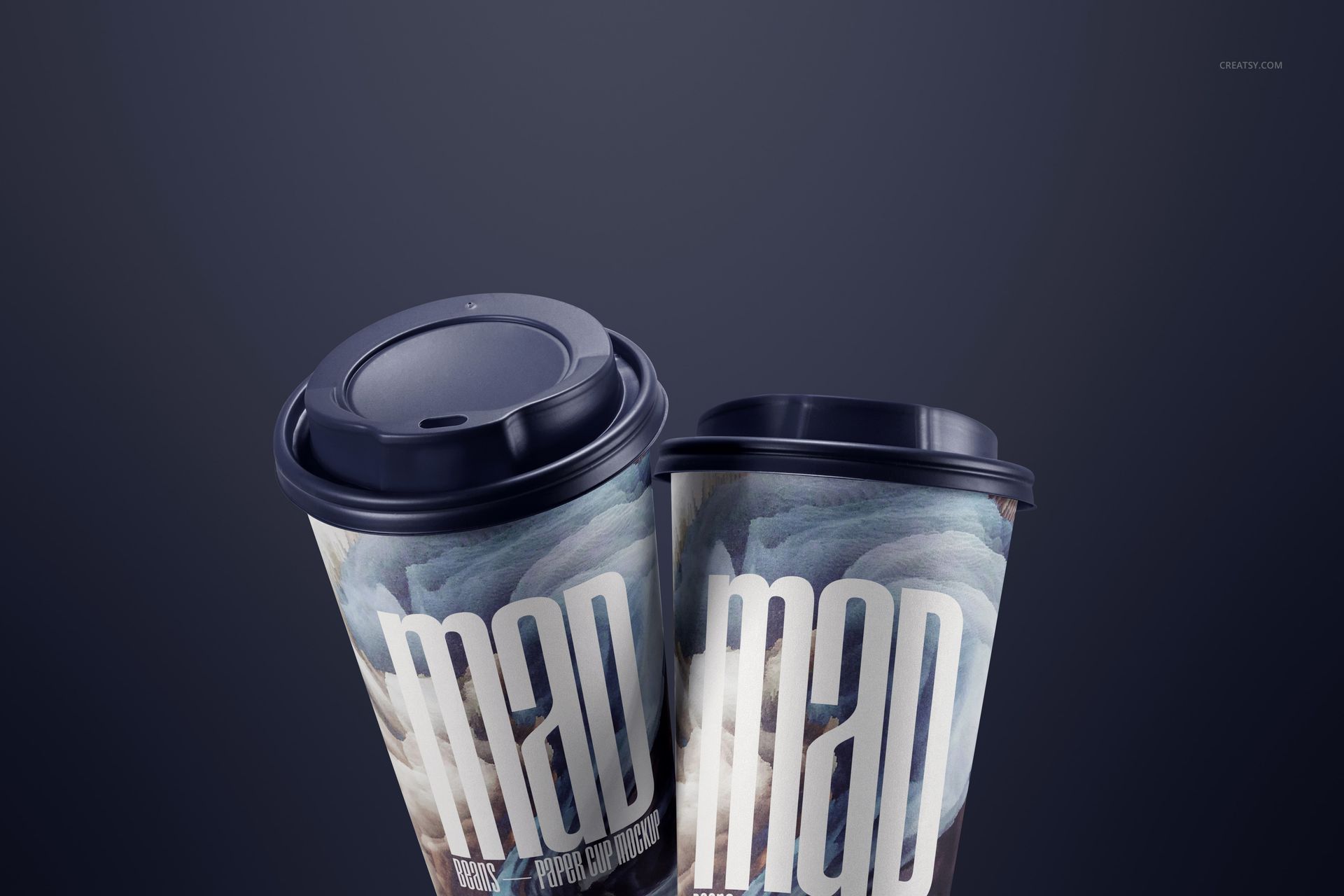 PSD mockup showing a pair of paper cups with artistic prints and dark lids, angled together on a smooth, dark background.