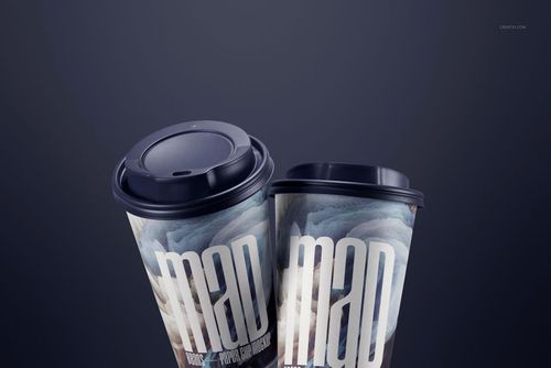 PSD mockup showing a pair of paper cups with artistic prints and dark lids, angled together on a smooth, dark background.