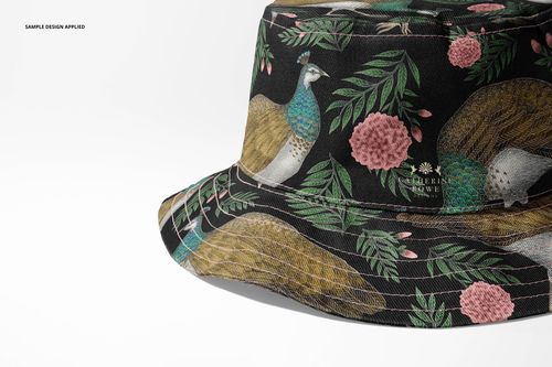 Front angled view of a reversible bucket hat mockup featuring a black background with peacock and floral pattern.
