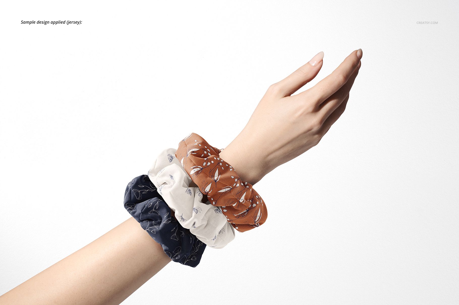 PSD mockup featuring a hand adorned with different colored and patterned hair scrunchies, set on a minimal white scene.