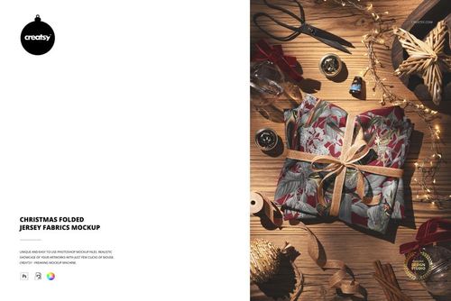 Christmas folded jersey fabric mockup featuring holiday motifs, ribbon, and decorative items on a wooden tabletop.