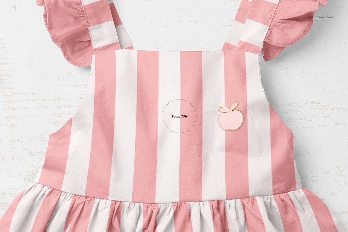 Front view of a baby dress mockup with wide pink and white vertical stripes, ruffled sleeves, and an apple patch detail.
