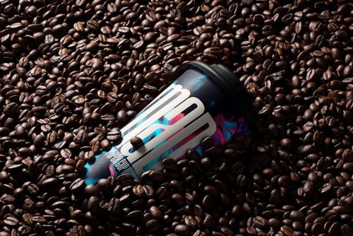 Front view of a paper cup mockup with a black lid and vibrant graphics, surrounded by dark coffee beans.