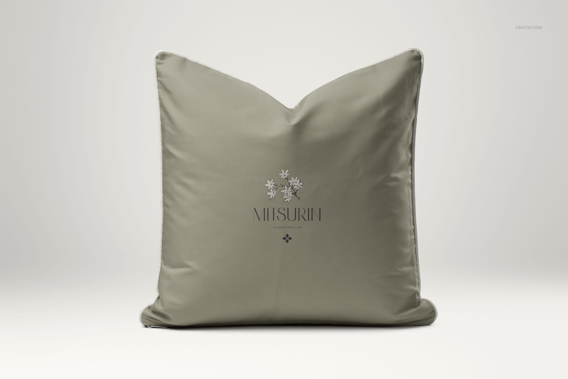 Reversible cushion mockup showing a soft green pillow with piped trim and simple floral artwork, photographed from the front.