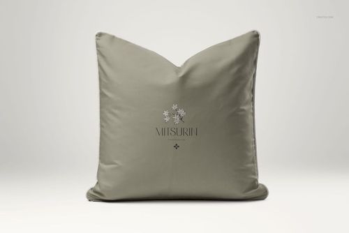 Reversible cushion mockup showing a soft green pillow with piped trim and simple floral artwork, photographed from the front.