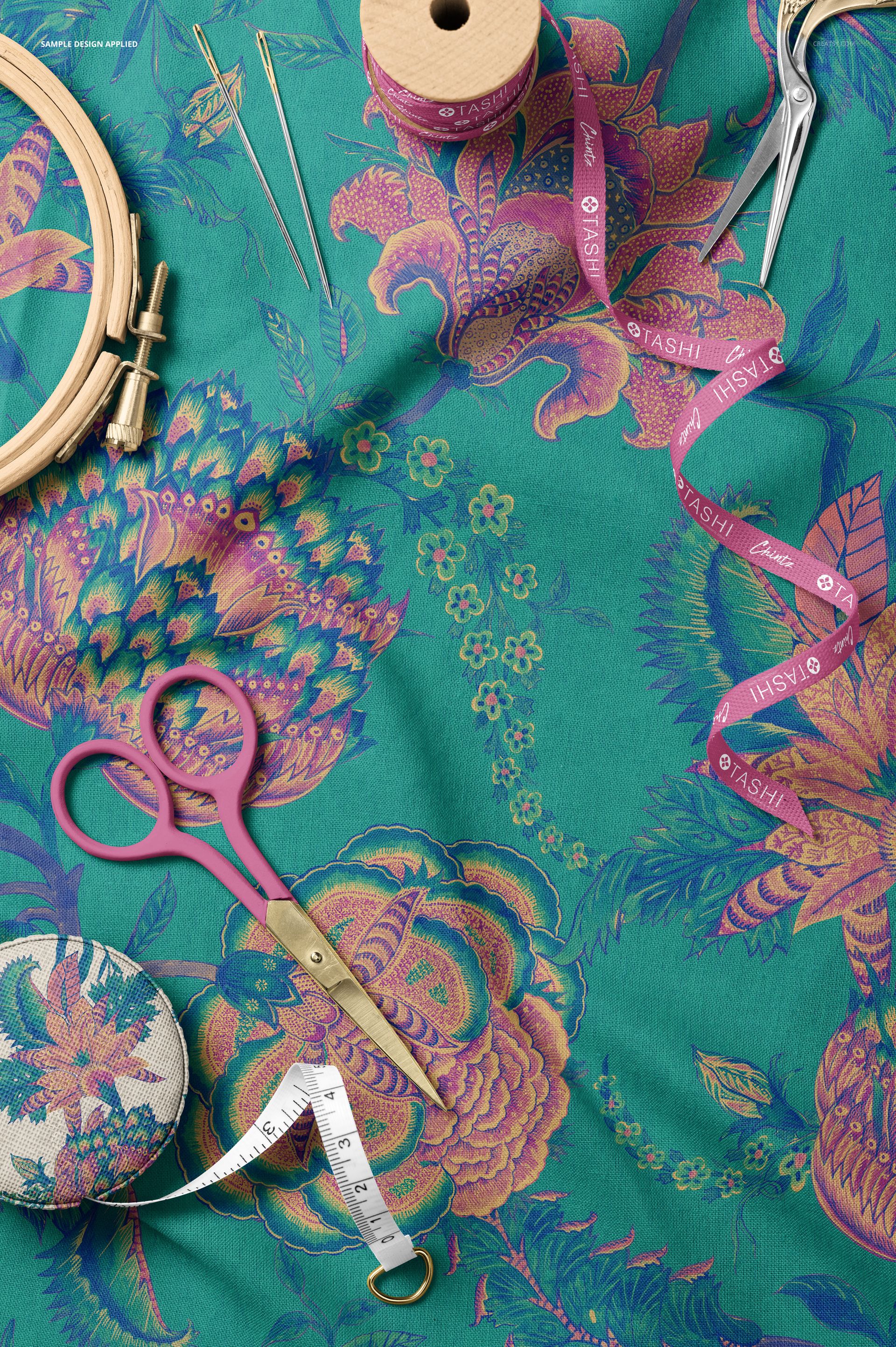 Top view of sewing tools including scissors, tape measure, and embroidery hoop on patterned cotton fabric mockup.