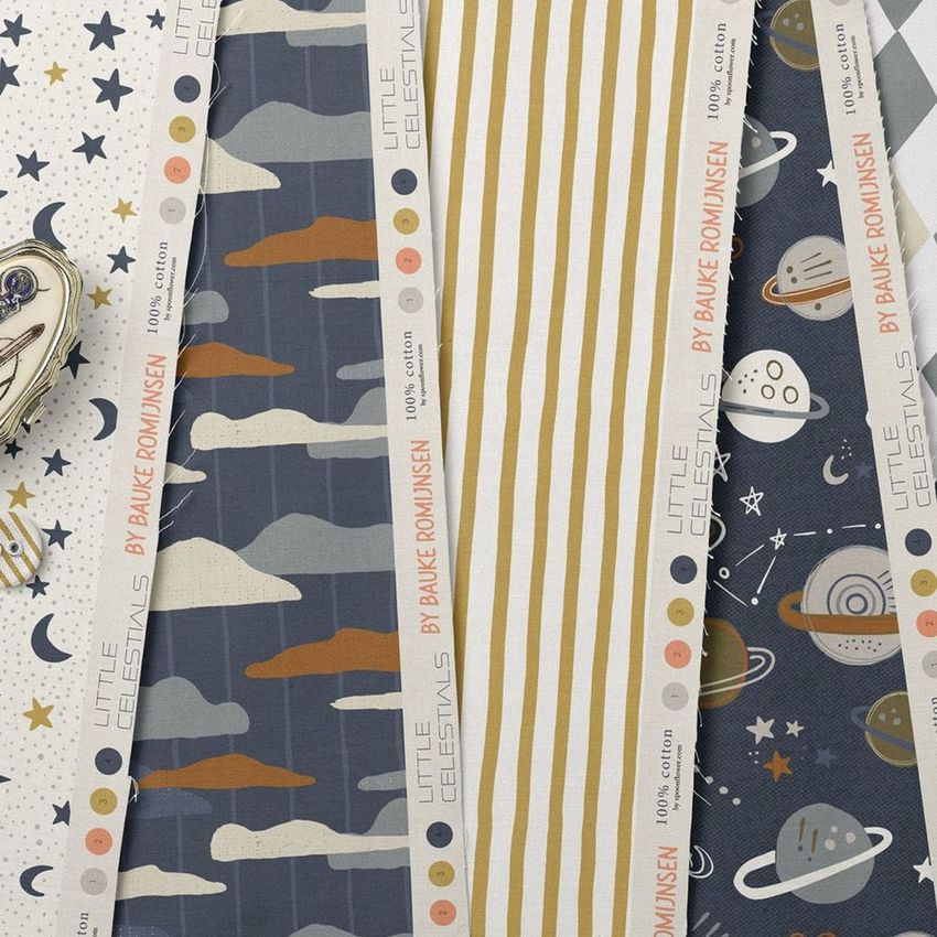 Cotton fabric sample mockup featuring several fabric strips with celestial-themed patterns, including stars, planets, and clouds.