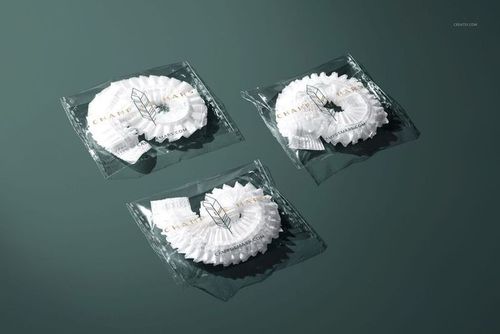 PSD mockup featuring three individually wrapped hotel shower caps arranged on a flat, dark green surface.