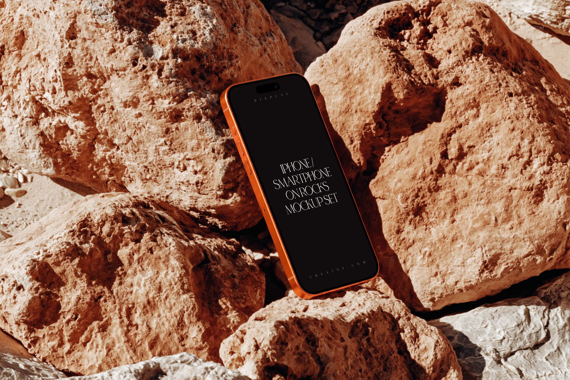 PSD mockup of an iPhone device positioned vertically among rugged brown rocks, front view scene.