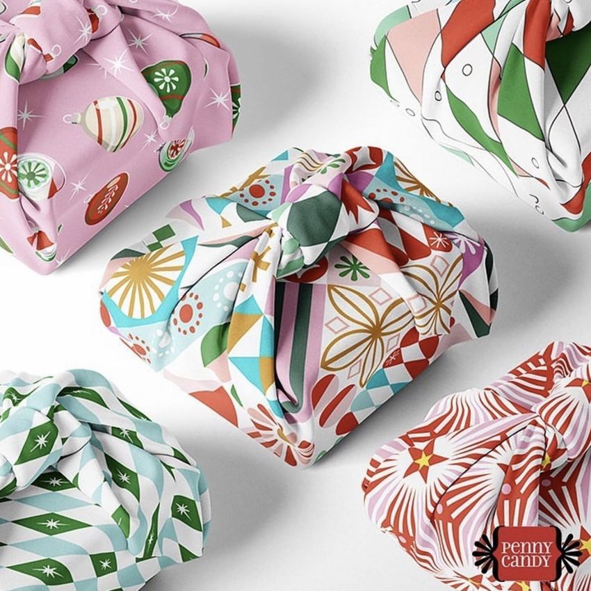 Fabric gift wrap mockup featuring five wrapped boxes with colorful geometric and holiday-themed patterns on a white background.