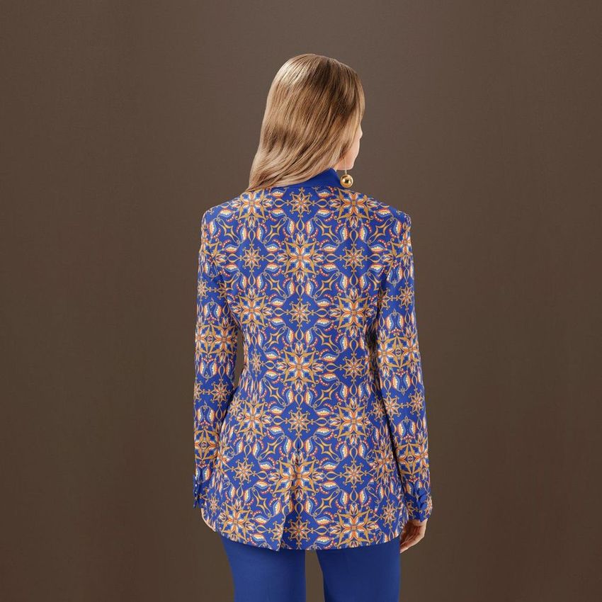 Woman wearing a blue and gold patterned blazer and trousers mockup set, seen from behind against a plain brown background.