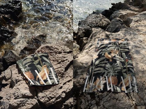 Tropical patterned waffle beach towel mockup shown folded and laid flat on natural rocks by the Croatian shoreline.