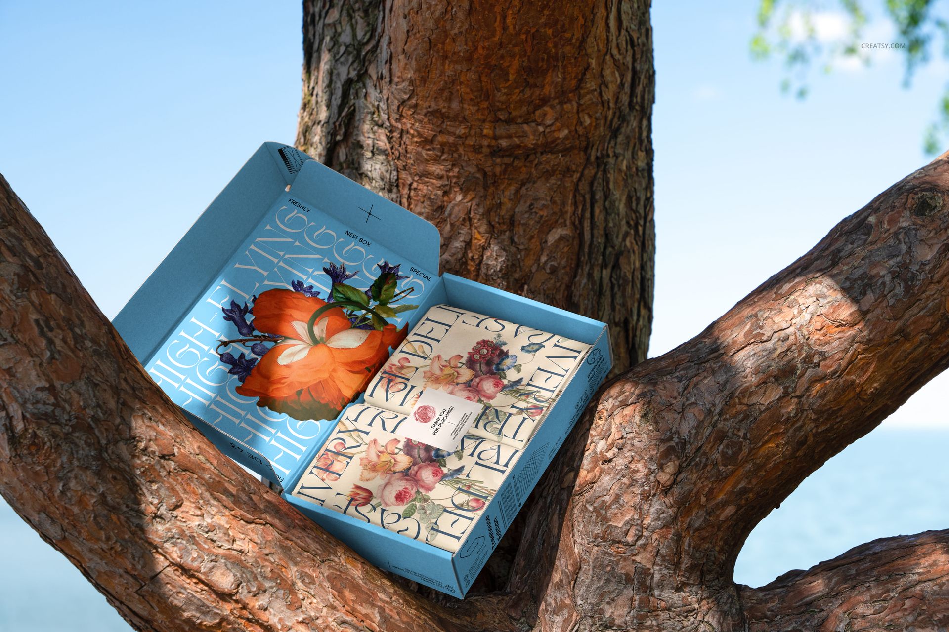Open mailing box mockup featuring a colorful flower pattern and bold lettering, placed on a textured tree trunk.