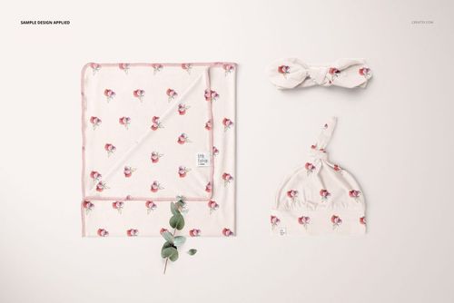 Swaddle set mockup featuring a folded blanket, knotted baby hat, and headband with pink floral pattern on cream fabric.