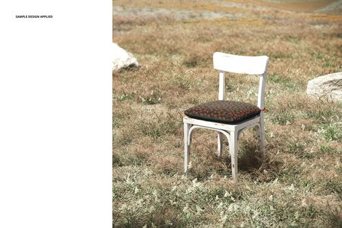 PSD mockup of a vintage chair with a decorative cushion, photographed outside on a sunlit, earthy landscape.