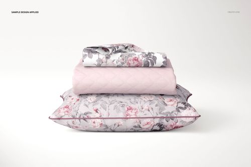 Front view of a pillow, coverlet, and pillowcase mockup with a floral pattern in soft pink and gray tones on a white background.