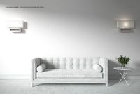 PSD mockup of a minimalist room with a light gray velvet sofa, two wall lamps, and a decorative side table.