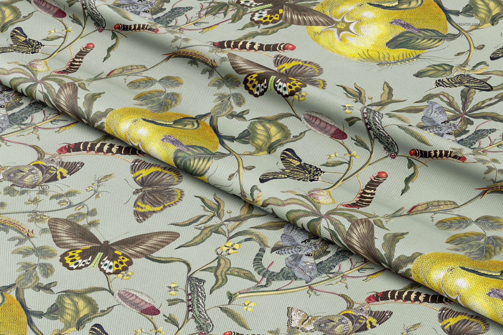 Polyester drapery fabric with a botanical pattern featuring butterflies, caterpillars, and fruit, shown in a folded mockup.