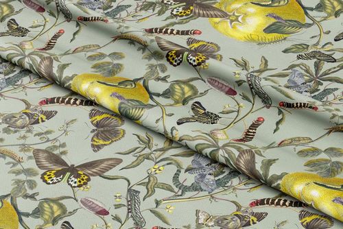 Polyester drapery fabric with a botanical pattern featuring butterflies, caterpillars, and fruit, shown in a folded mockup.