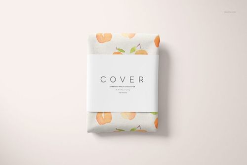 PSD mockup of a multi-use cover, neatly folded with a peach motif, presented with a white wrap band from a top angle.