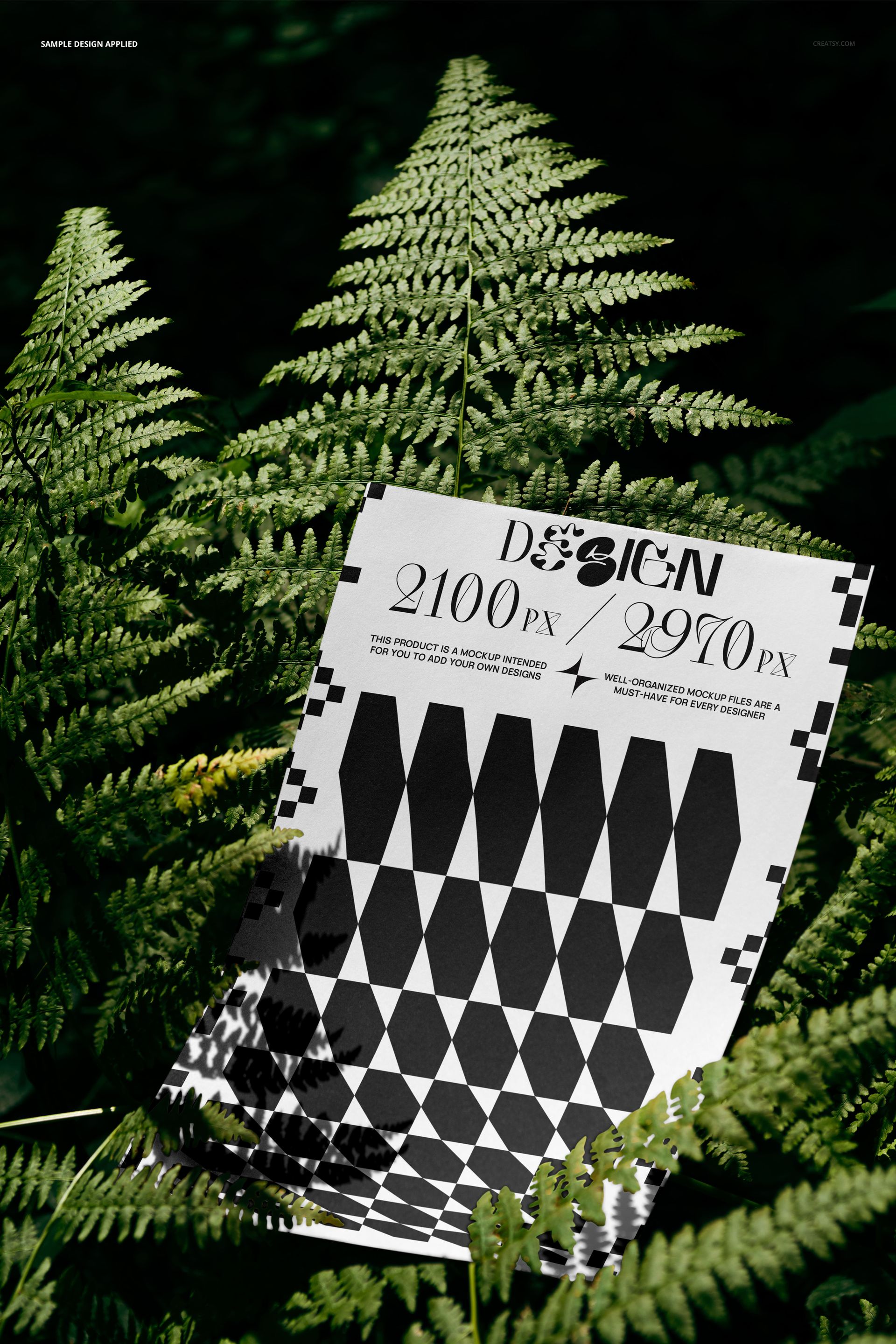 PSD mockup showing a rectangular poster with bold black and white design resting on vibrant fern foliage outdoors.